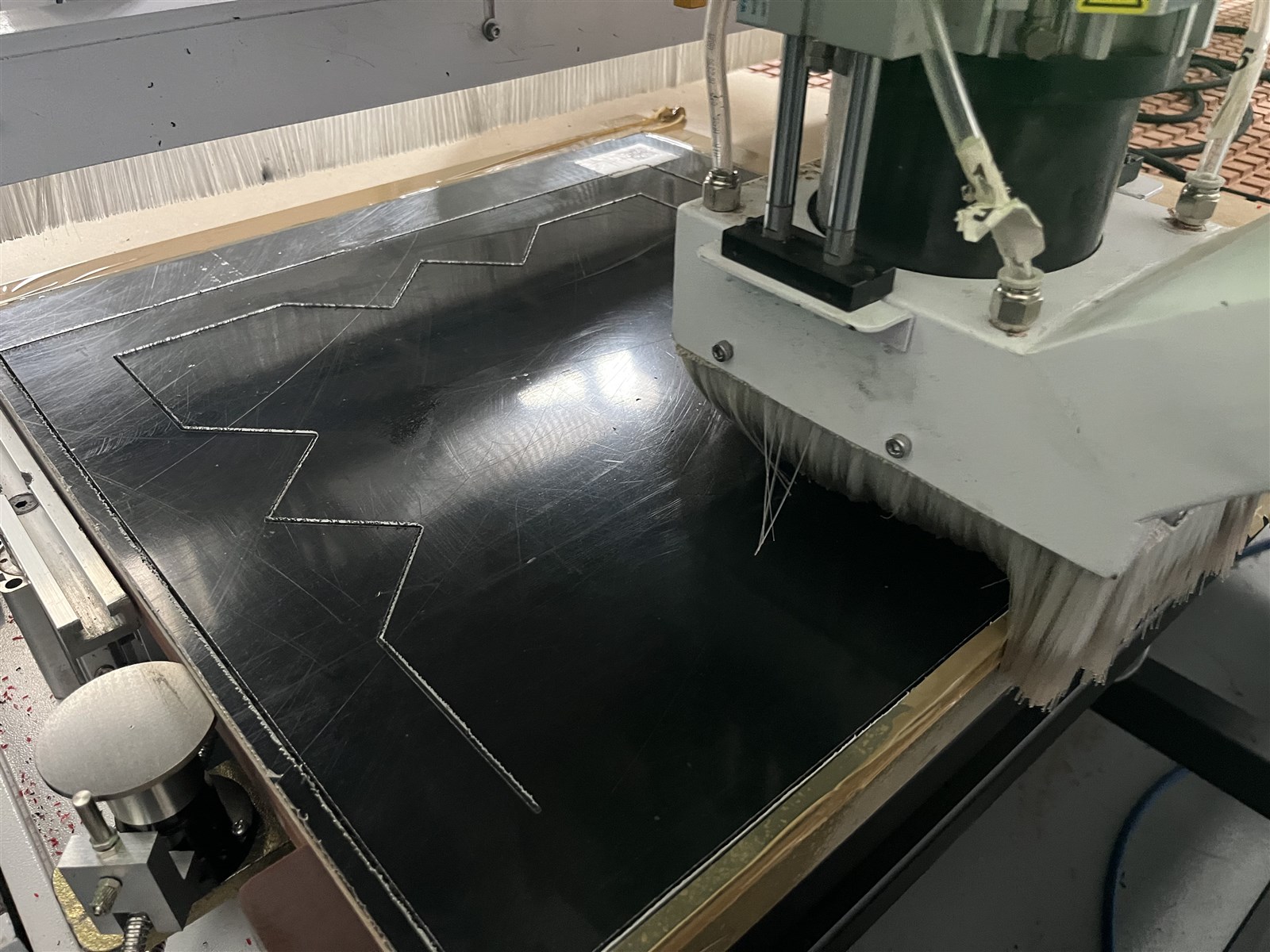 CNC frézka při obrábění černé desky technického plastu
