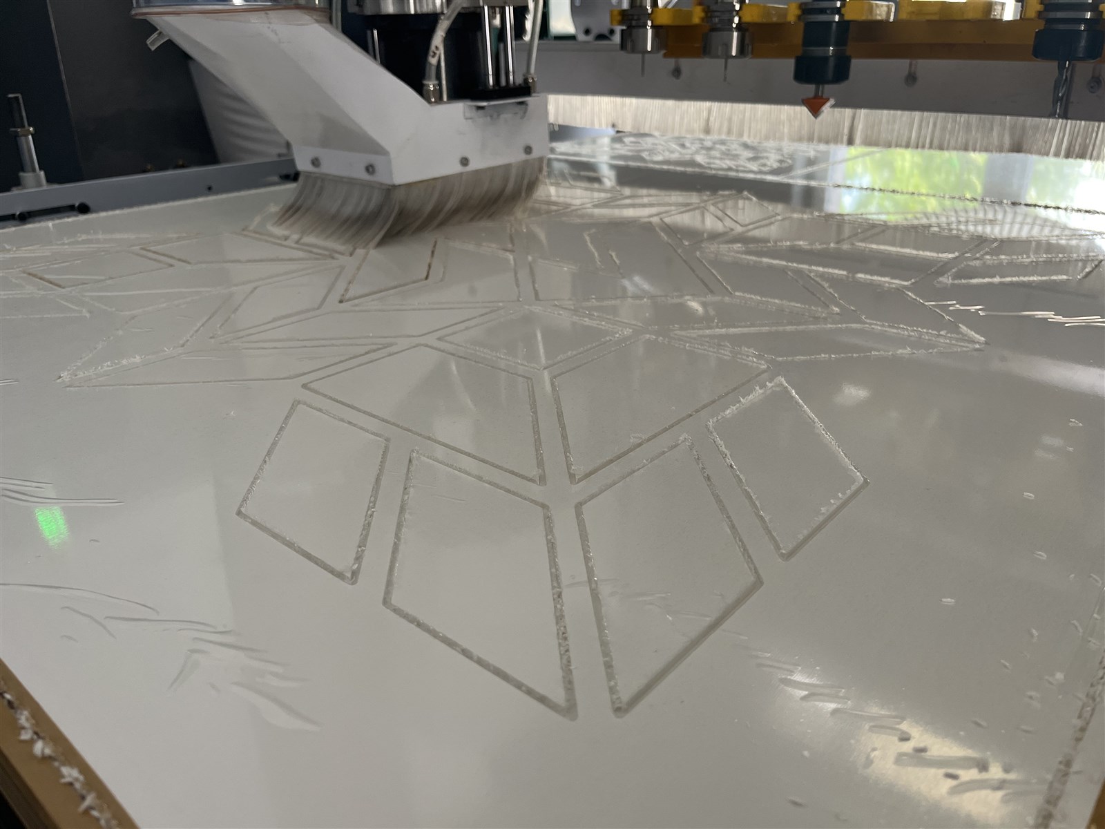 CNC frézka při vyřezávání dílů z bílé desky technického plastu